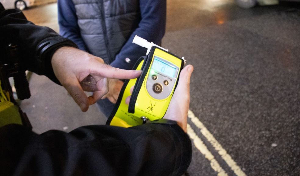 Pictured: Officer holding digital breathalyser device displaying '0' reading