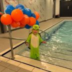 Baby in fancy dress stood by pool
