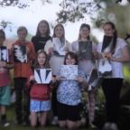 Teen holding up their art for photo in forest
