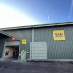 A large industrial warehouse building with green metal siding and a yellow signreading 'VAN GUARD'