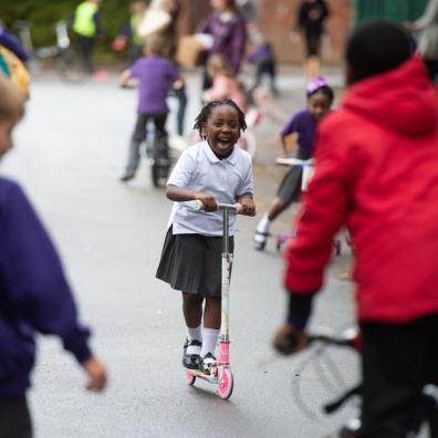 Photo of children playing on scooters and bikes