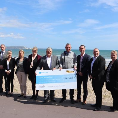 Group of people holding a large cheque on a beach