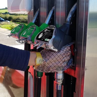 hand wearing GripHero glove gripping a grey fuel pump