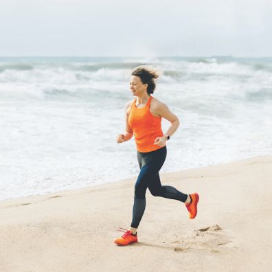 Woman running along a beach close to the shoreline