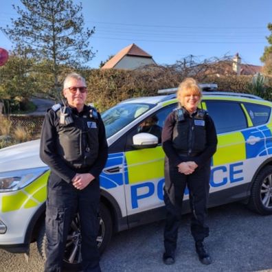 2 police officers standing beside police car